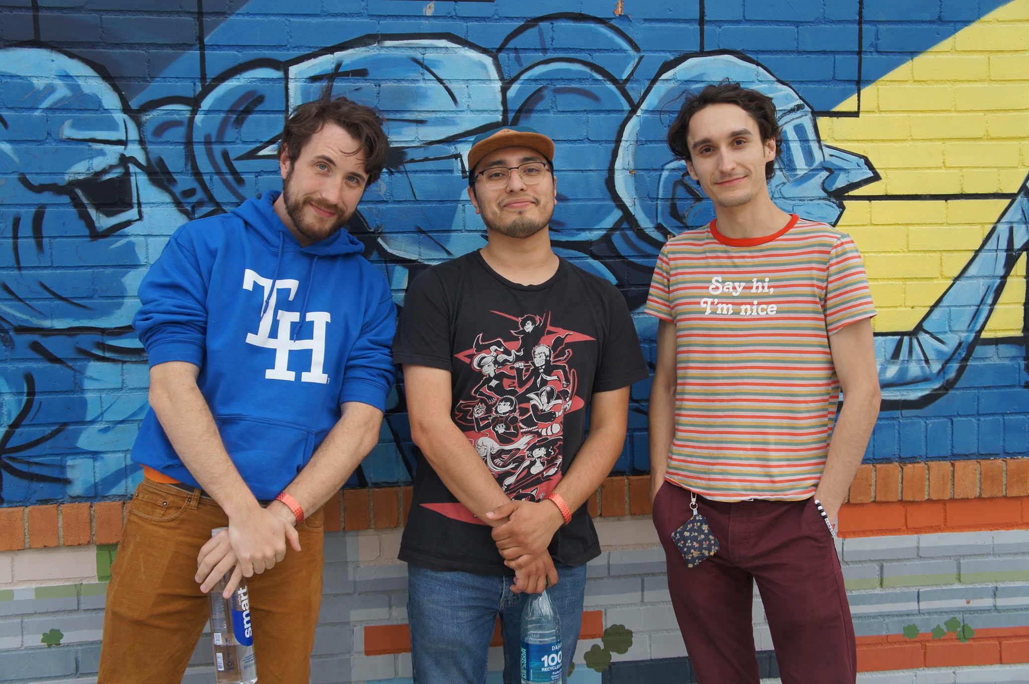 Image of Alan Macchiarolo, Matt Garcia, and Emerson Harris of the Toxhards standing next to each other in front of a wall in the sun.